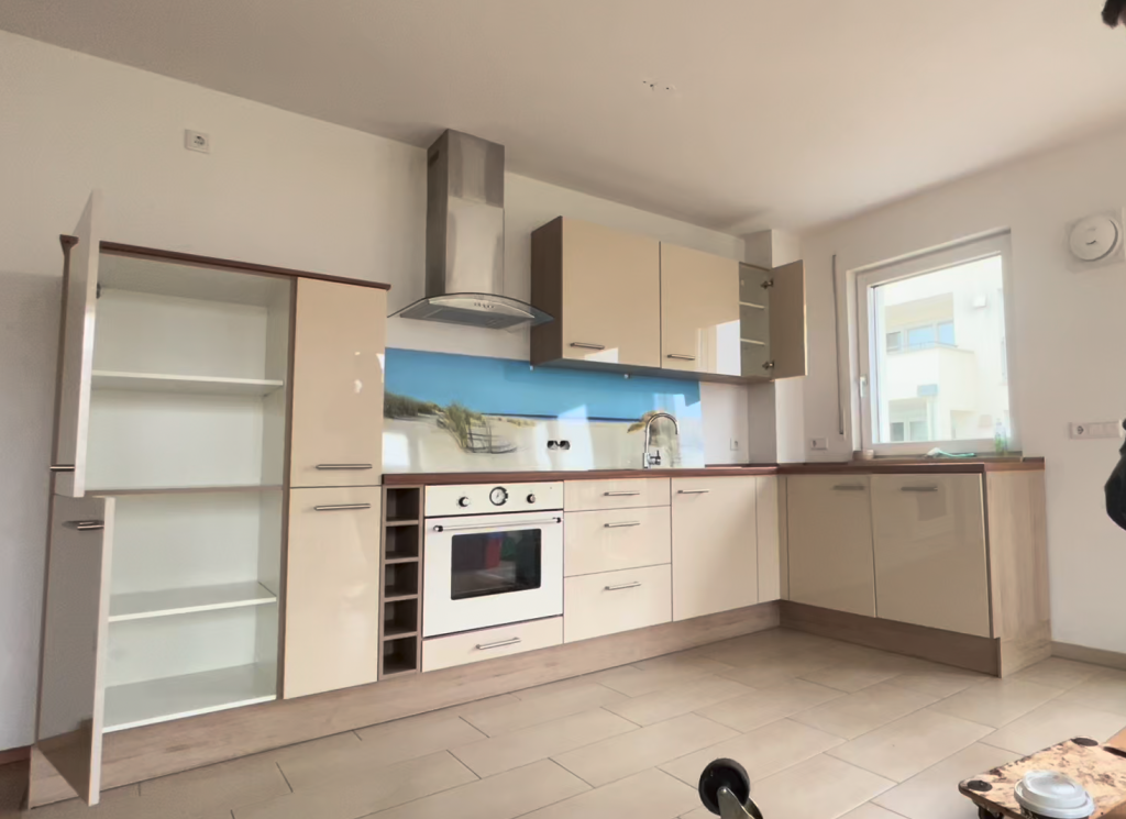 Moderne Einbauküche mit Hochglanzfronten, Herd, Spüle und Oberschränken.