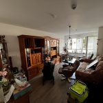 Wohnzimmer mit alten Holzmöbeln, braunem Sofa und voller Einrichtung vor Entrümpelung.