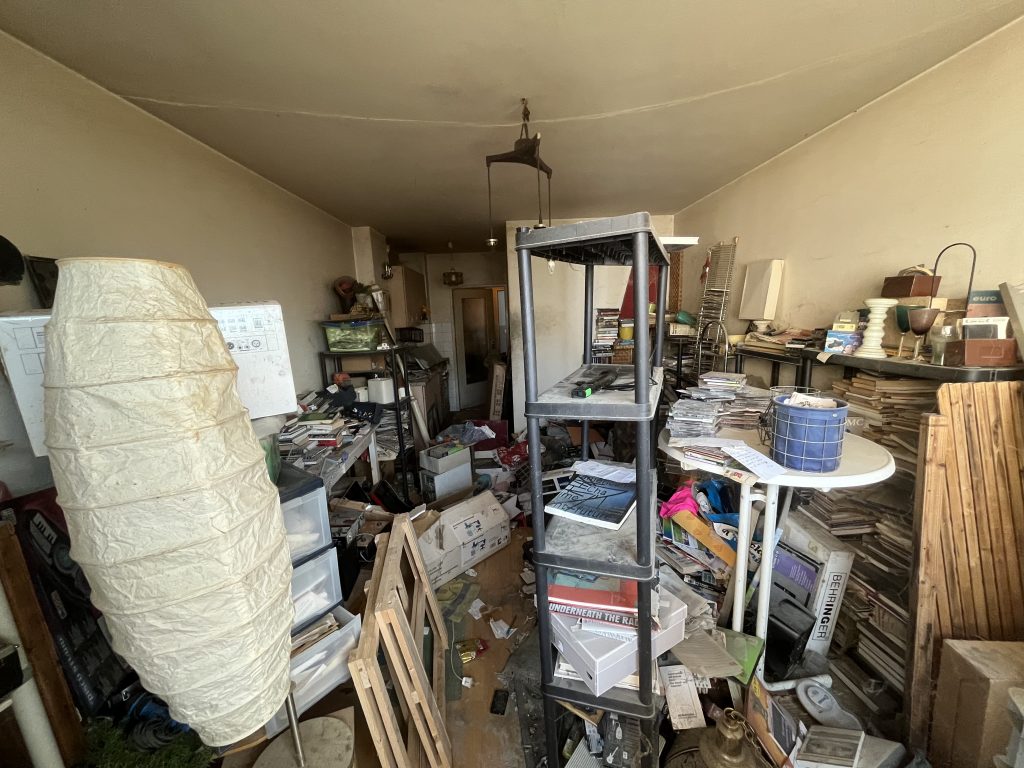 Messie-Wohnung mit chaotisch verstreuten Gegenständen, Möbeln und Unordnung, vor der Entrümpelung.