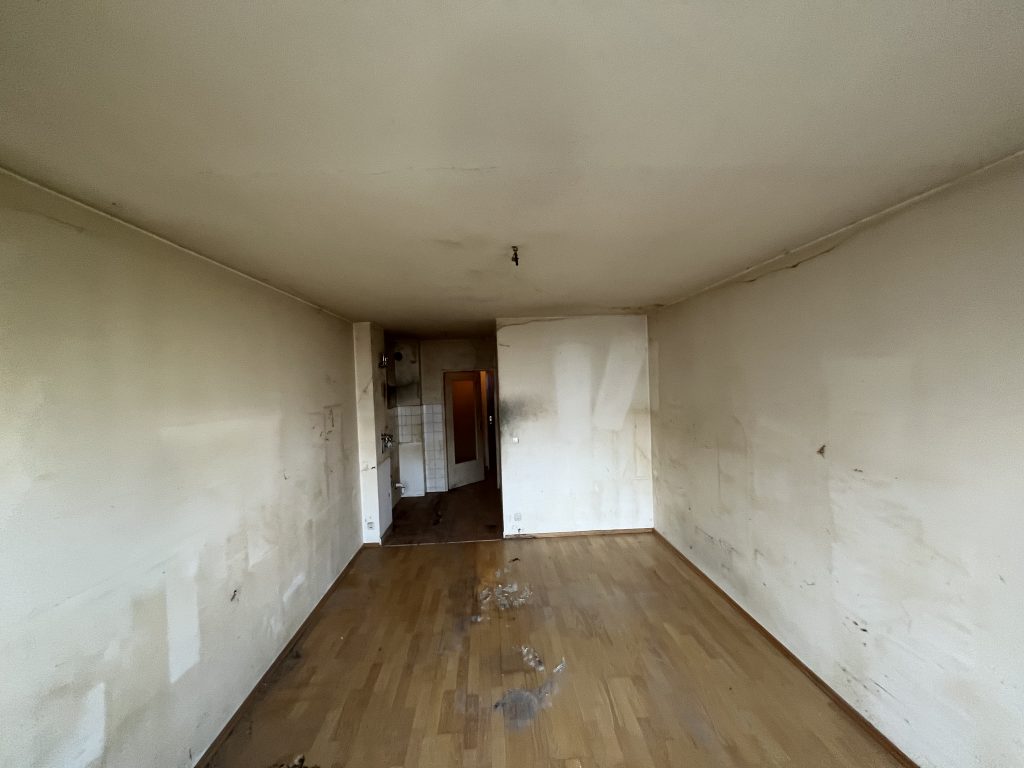 Messie-Wohnung mit sichtbarem Schmutz und unaufgeräumten Wänden und Boden, vor der Renovierung.