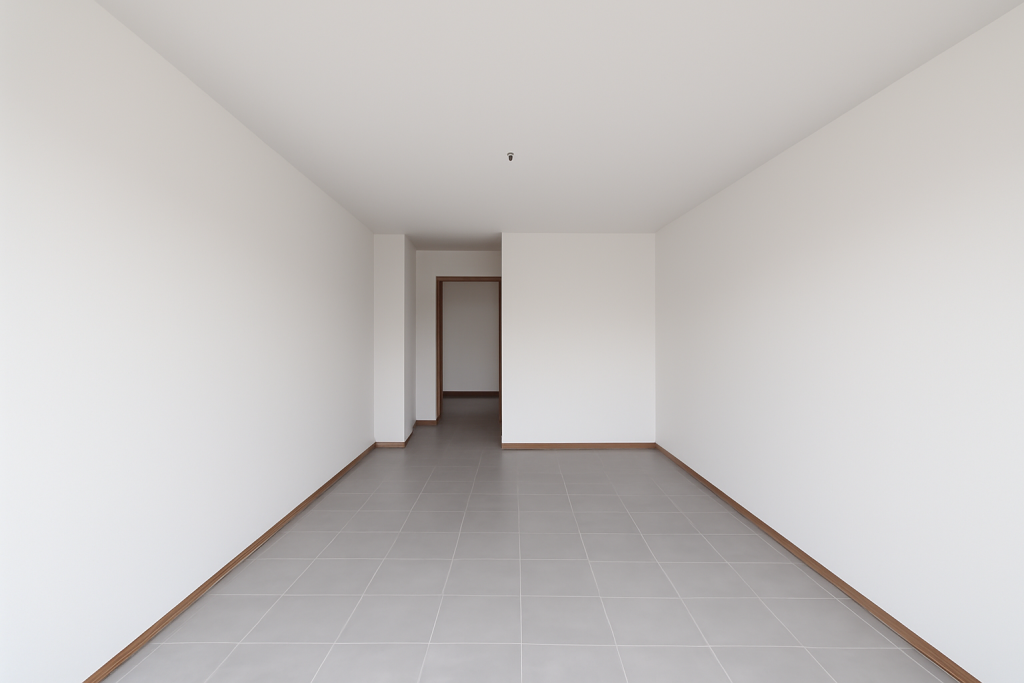 Renoviertes Zimmer mit frisch gestrichenen weißen Wänden und neuen grauen Fliesen auf dem Boden, modern und ordentlich.