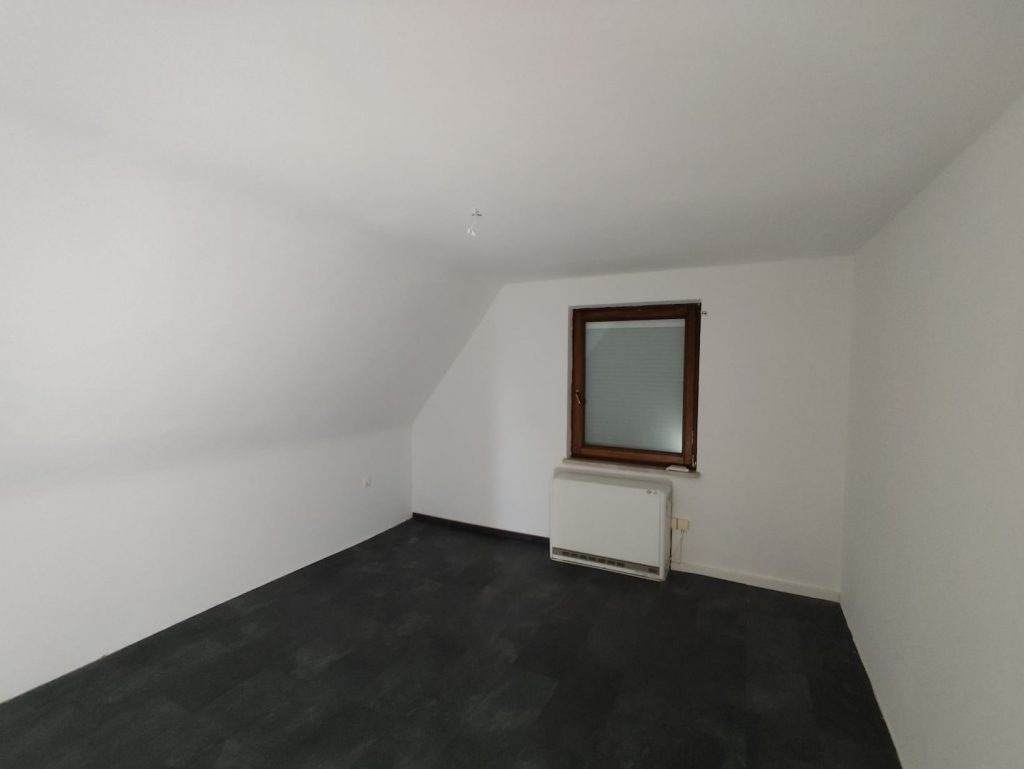 Renovierter Raum mit frisch gestrichenen Wänden und neuem Boden – professionelle Malerarbeiten und Bodenverlegung.