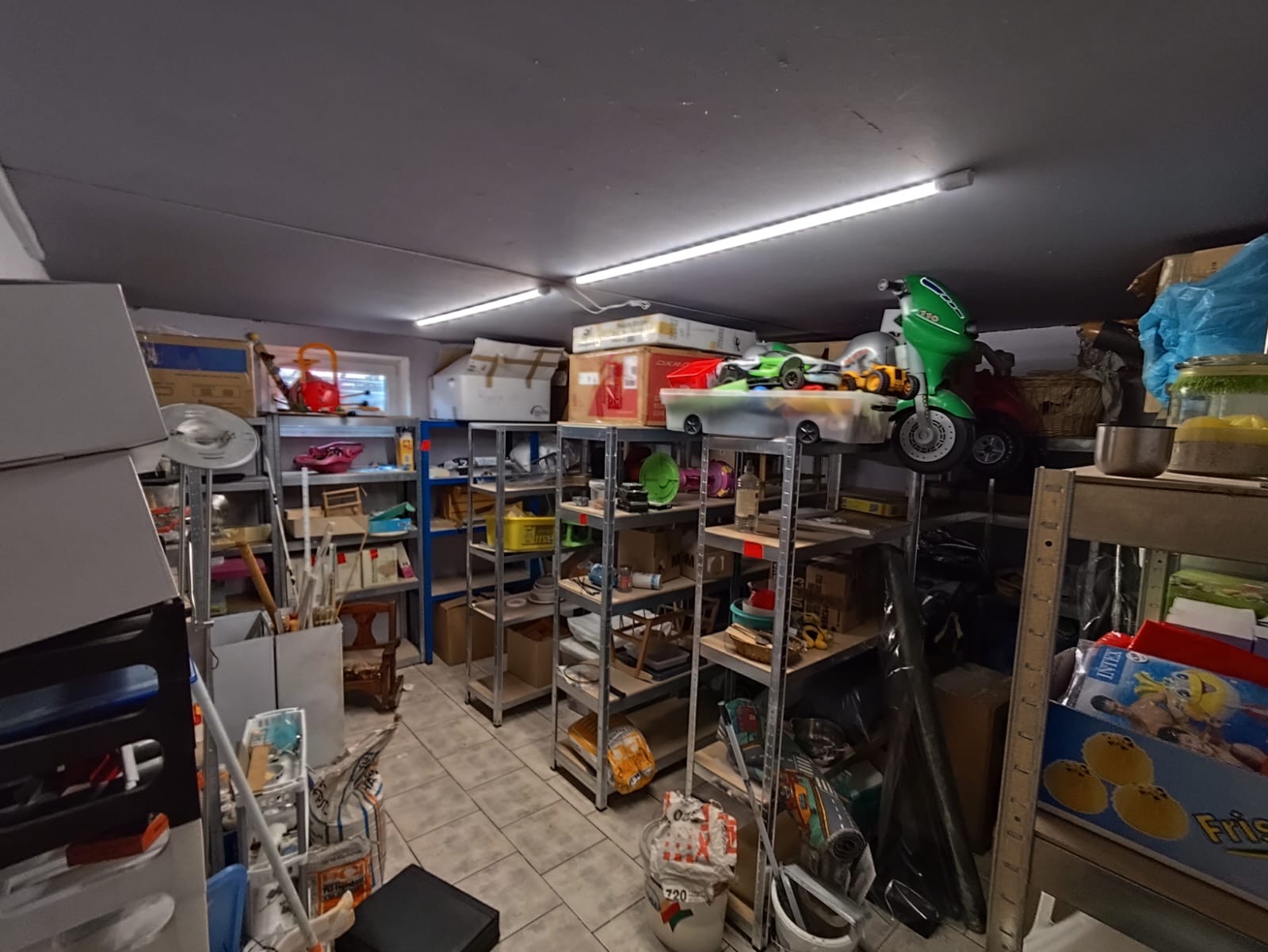 Überfüllter Kellerraum mit Regalen, Kartons und verschiedenem Gerümpel, ideal für eine professionelle Kellerentrümpelung.