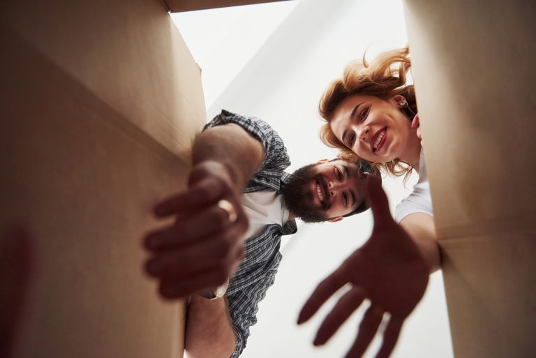 Glückliches Paar packt Kleidung aus Kartons in ihrem neuen Zuhause aus – Umzug